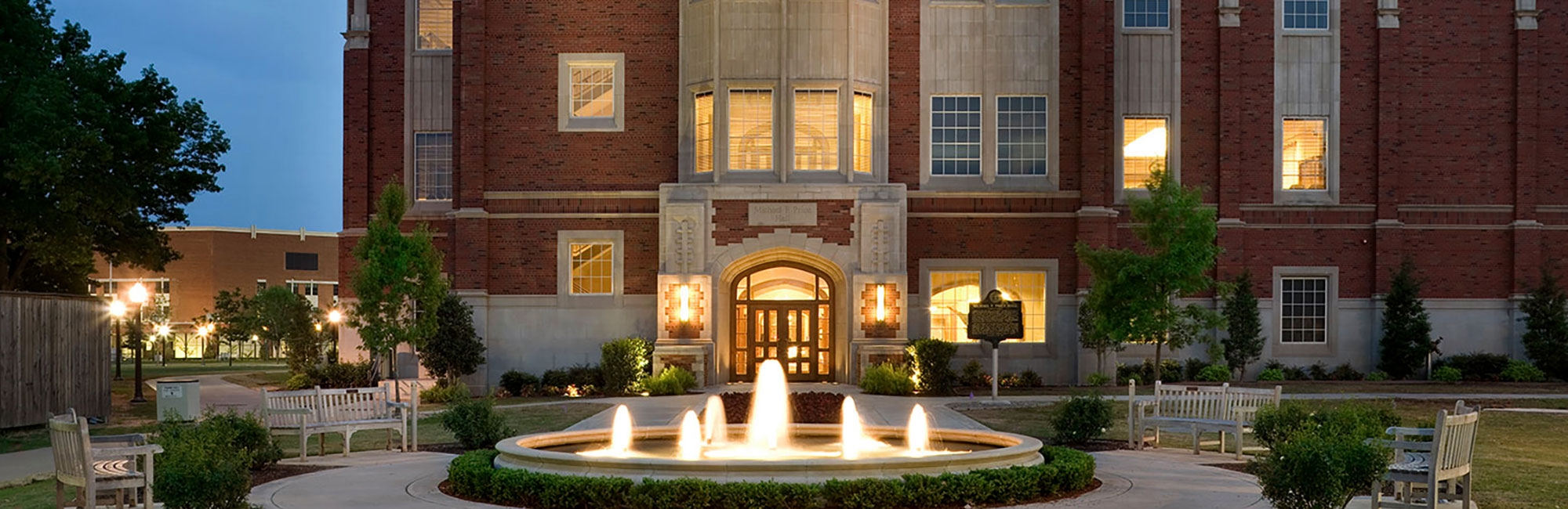 Exterior of Price Hall in the evening with subtle lighting and a fountain