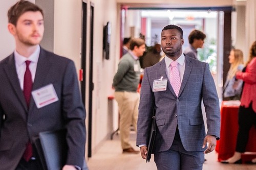 two young men in business attire walking down a hallway
