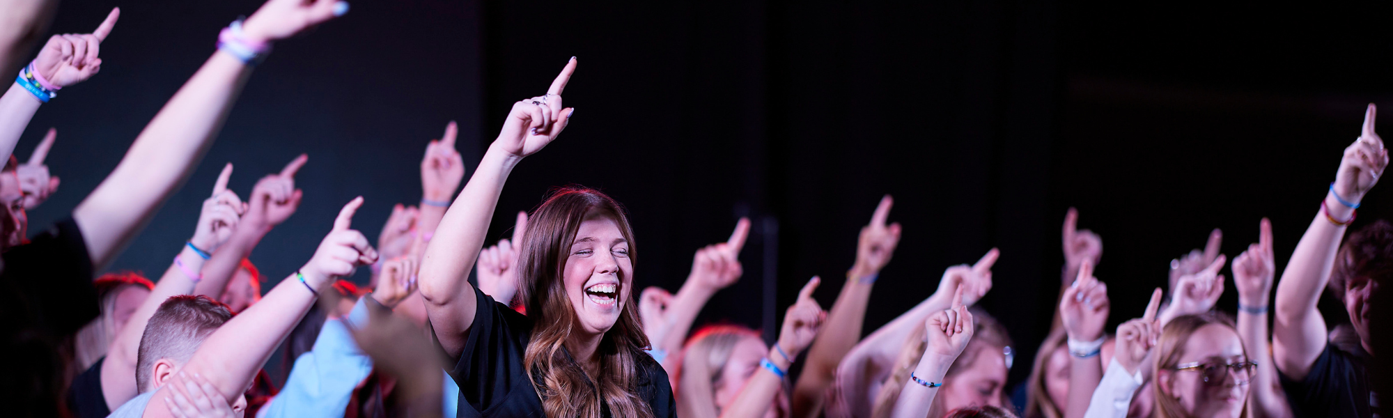 Participants at CAC's OU Dance Marathon holding one finger in the air while singing OU's alma mater.