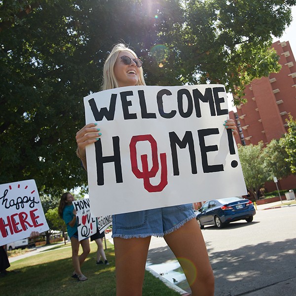 student holds up welcome sign