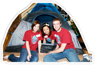 Three students sitting near a tent