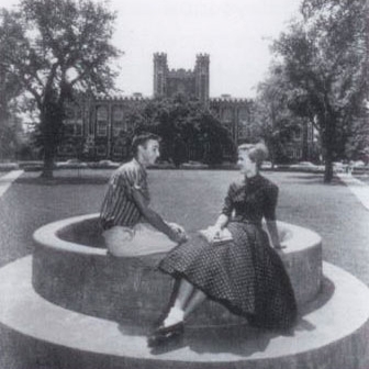 A black and white historical photo of a man and woman sitting on the Spoonholder, located on the North Oval lawn of the University of Oklahoma campus in Norman.