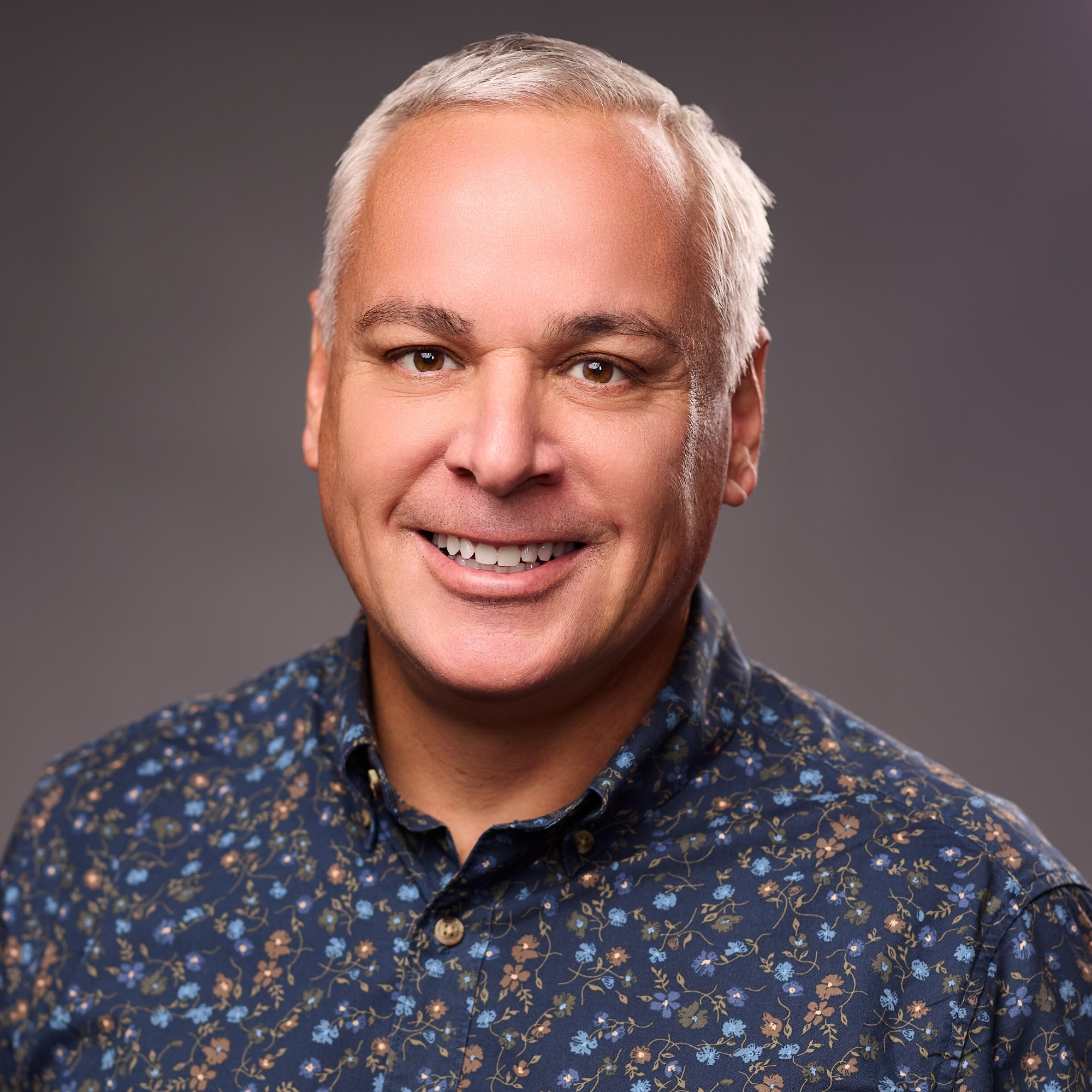 An O U flag on a lamppost, surrounded by greenery.