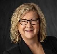 An O U flag on a lamppost, surrounded by greenery.