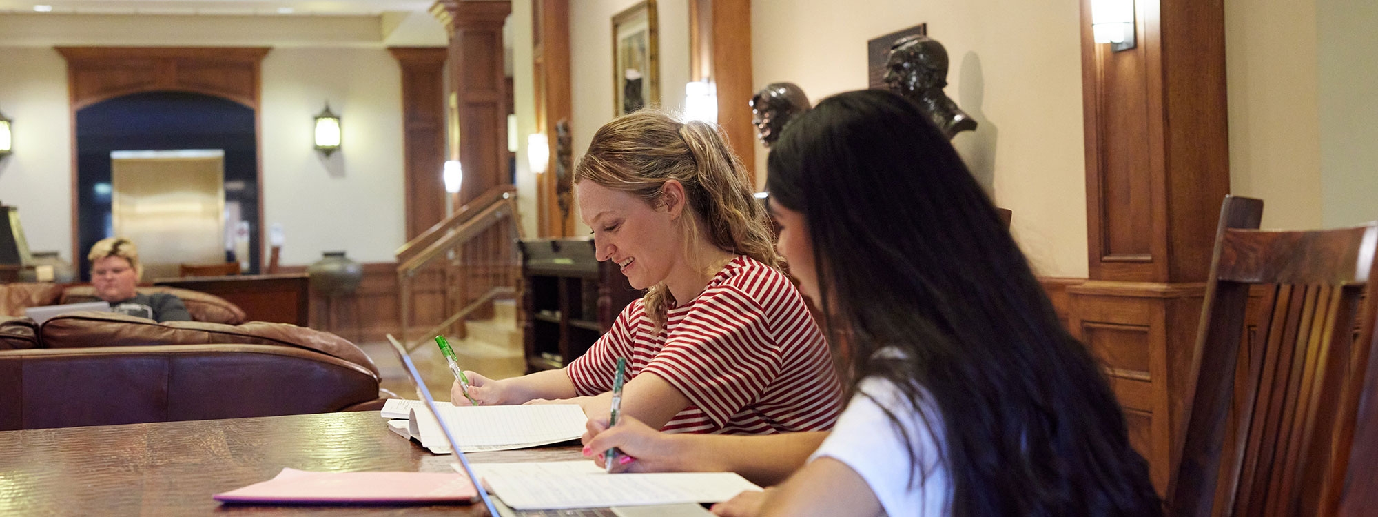 Two students sitting at a table with laptops.