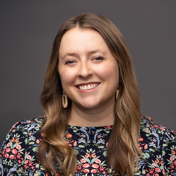 An O U flag on a lamppost, surrounded by greenery.