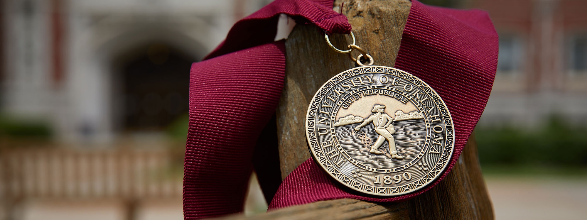 University of Oklahoma gold medallion on a crimson lanyard.