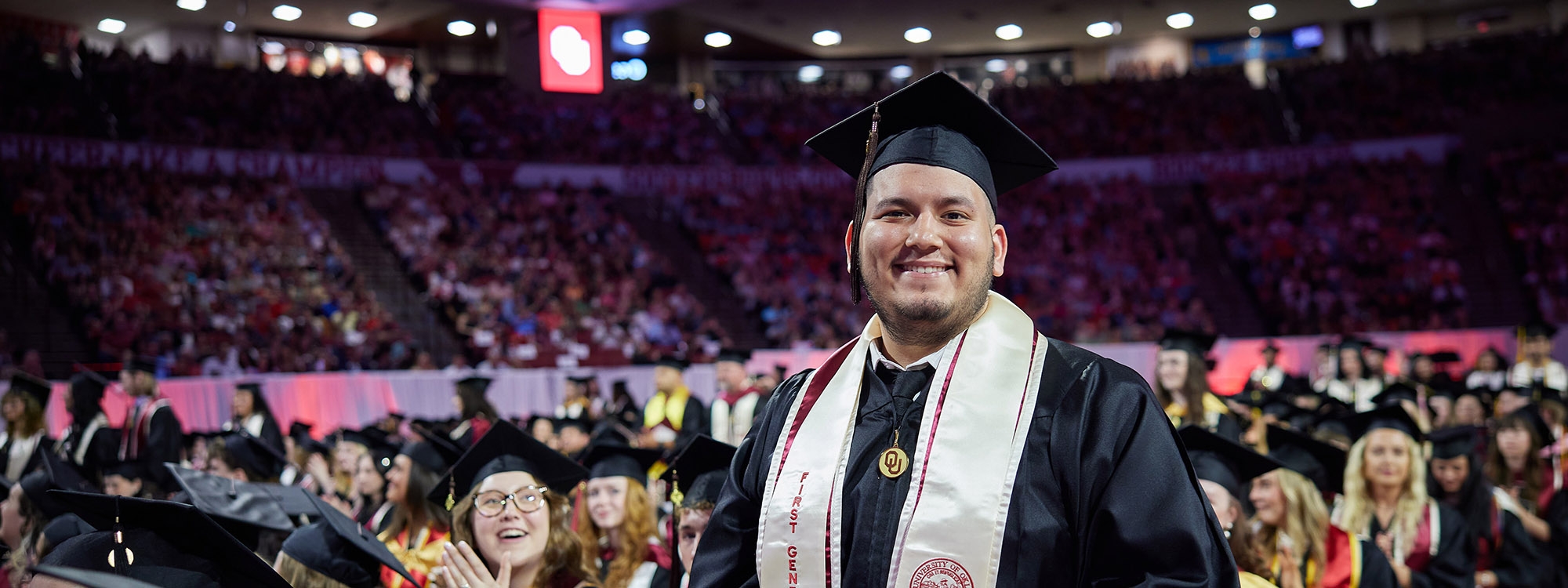 First Gen student standing amongst graduates before commencement ceremony.