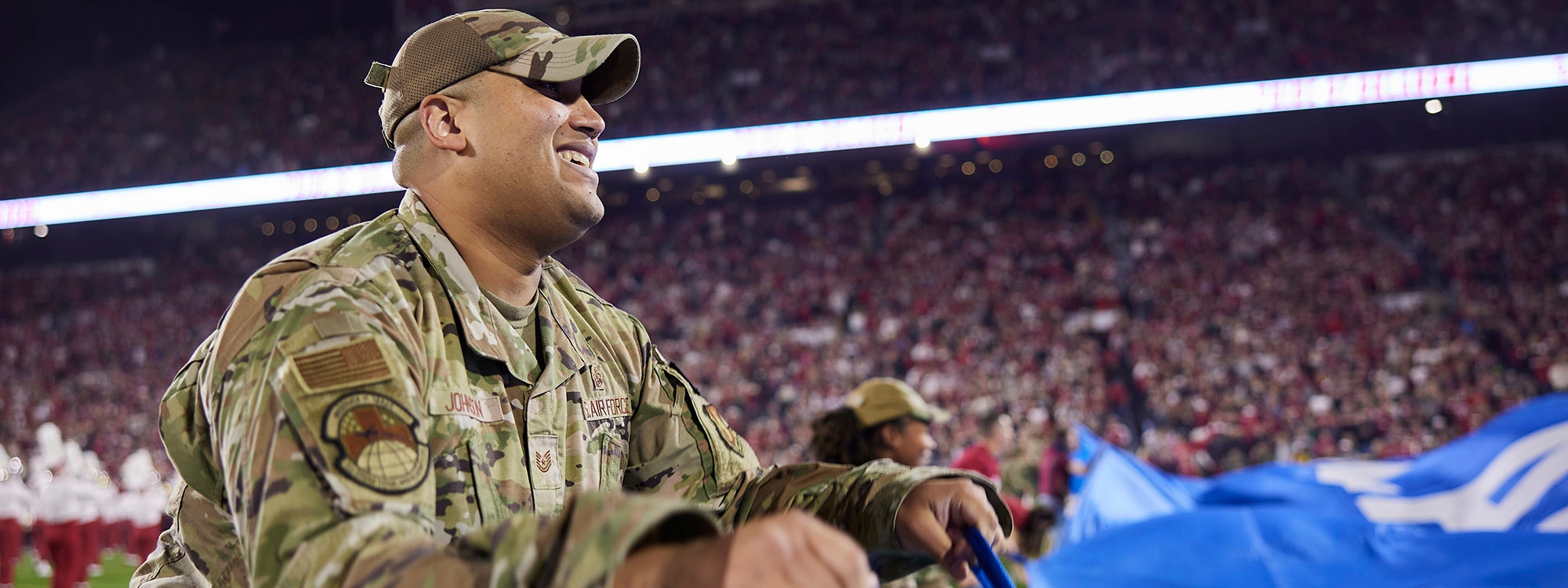 Military member in uniform holding part of the Oklahoma state flag before OU vs West Virginia game on November 11, 2023.