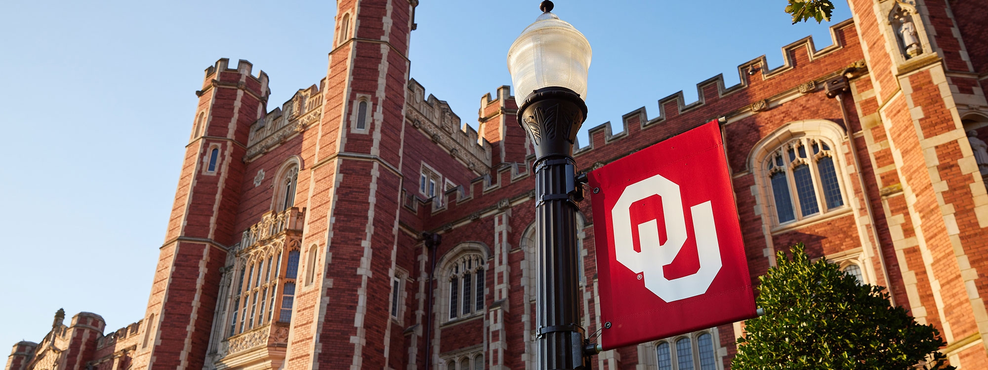 A lamppost with an OU flag in front of Evans Hall.
