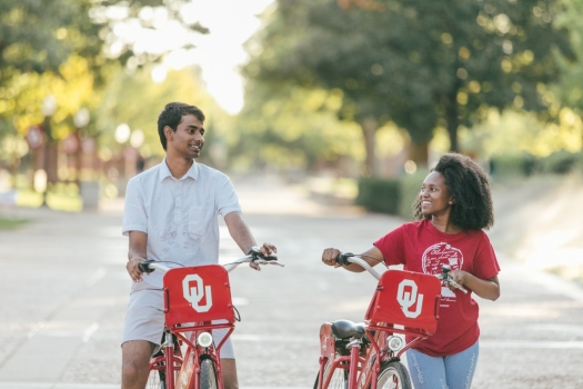 Two students walking bikes on campus