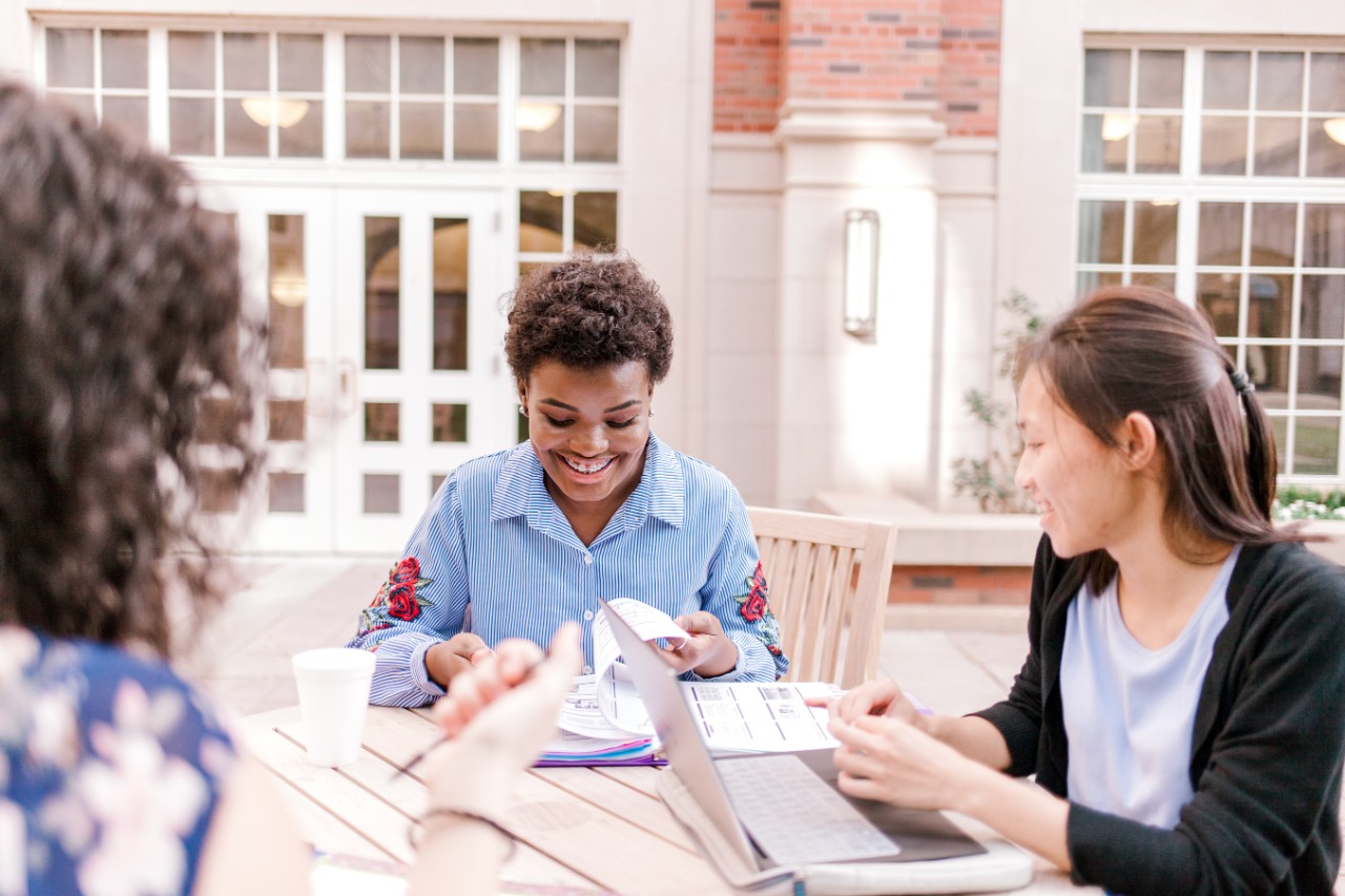 Three students sitting at a table outside Adams Hall
