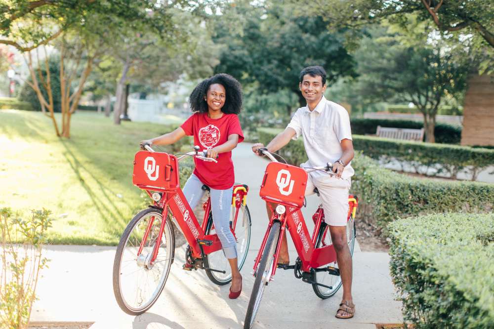 Two OU students riding bikes on campus