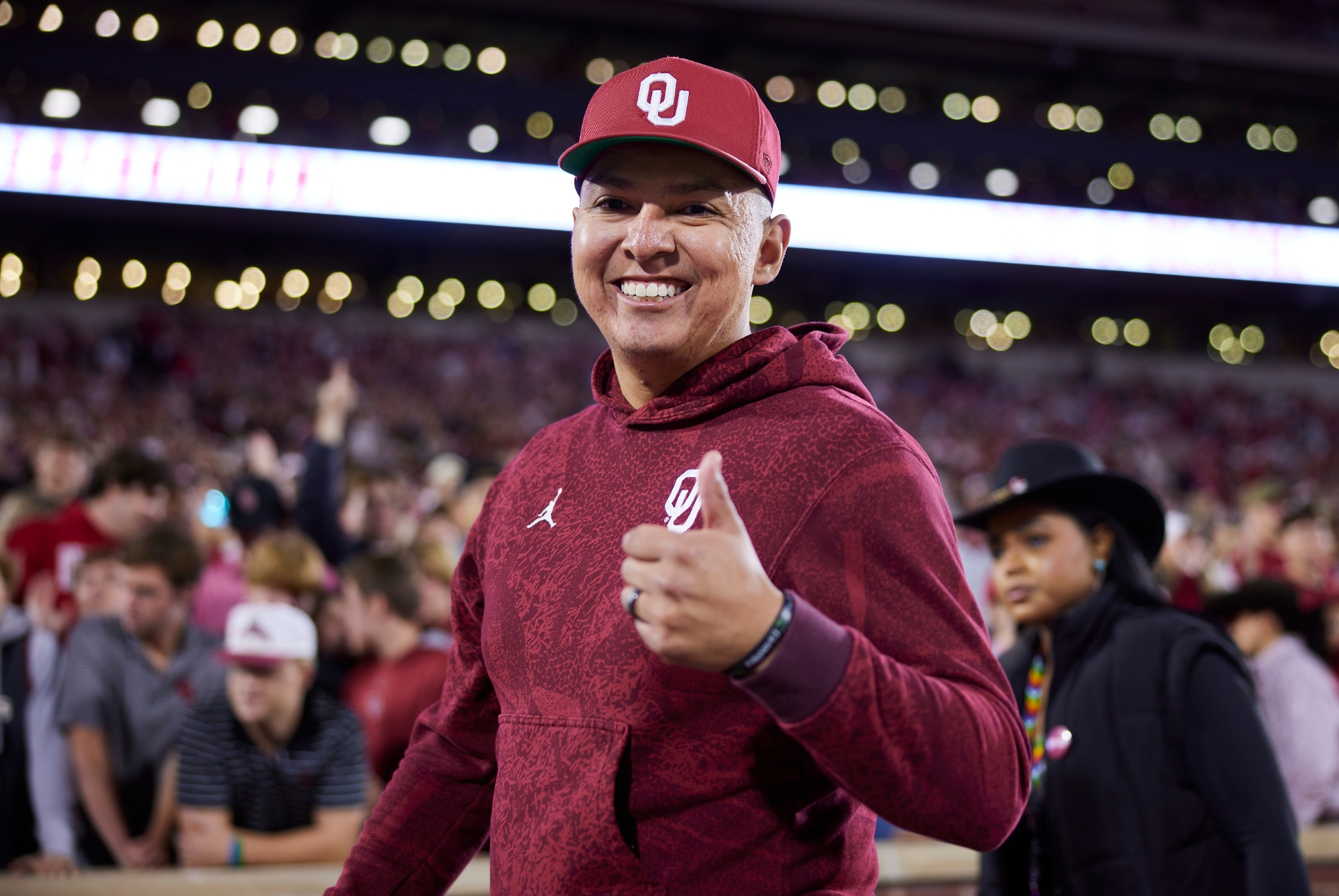 A man in an OU shirt and hat gives the camera a thumbs up