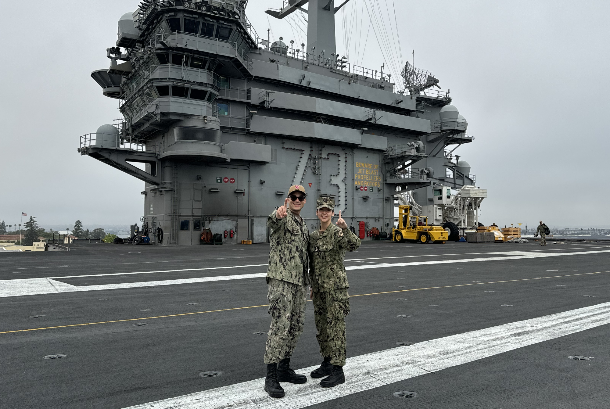 Aaron and classmate posing with a number one on an aircraft carrier.