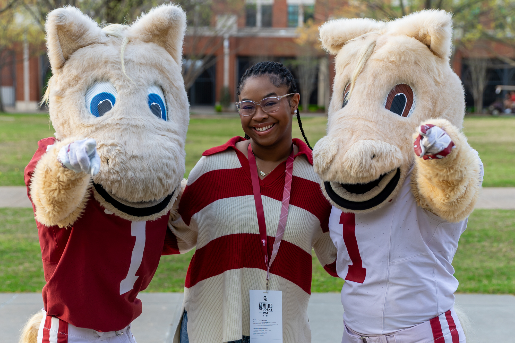 Student posing with OU Mascots Boomer and Sooner