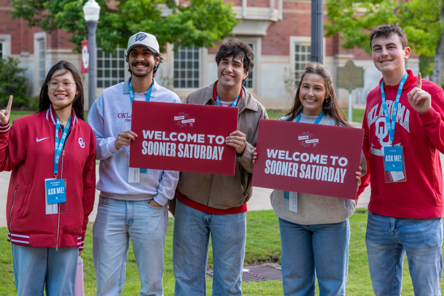 OU Students holding up a "Welcome to Sooner Saturday" sign