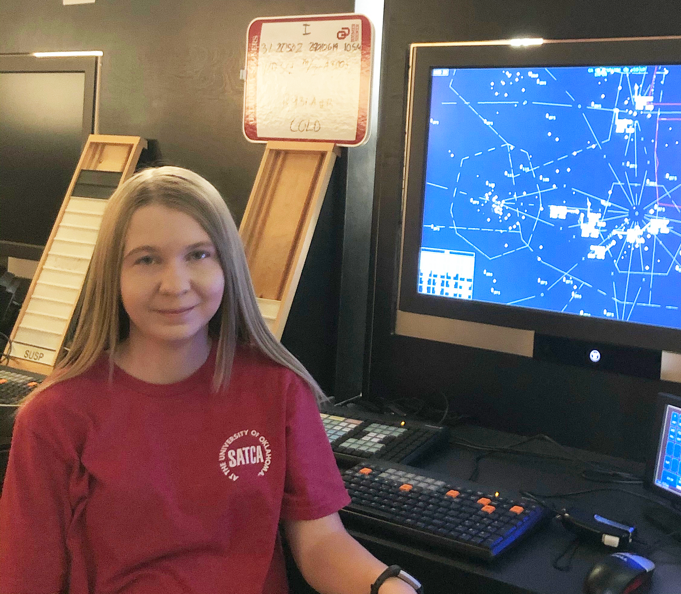 Taylor Shannon sitting in front of a computer screen with an Air traffic simulation running.