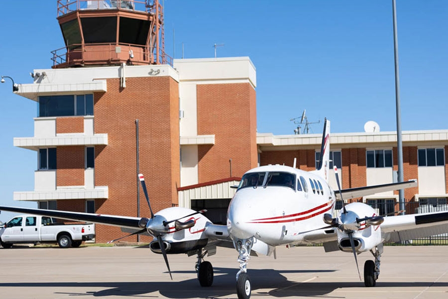 The control tower at Max Westheimer Airport, with an airplane in the foreground.