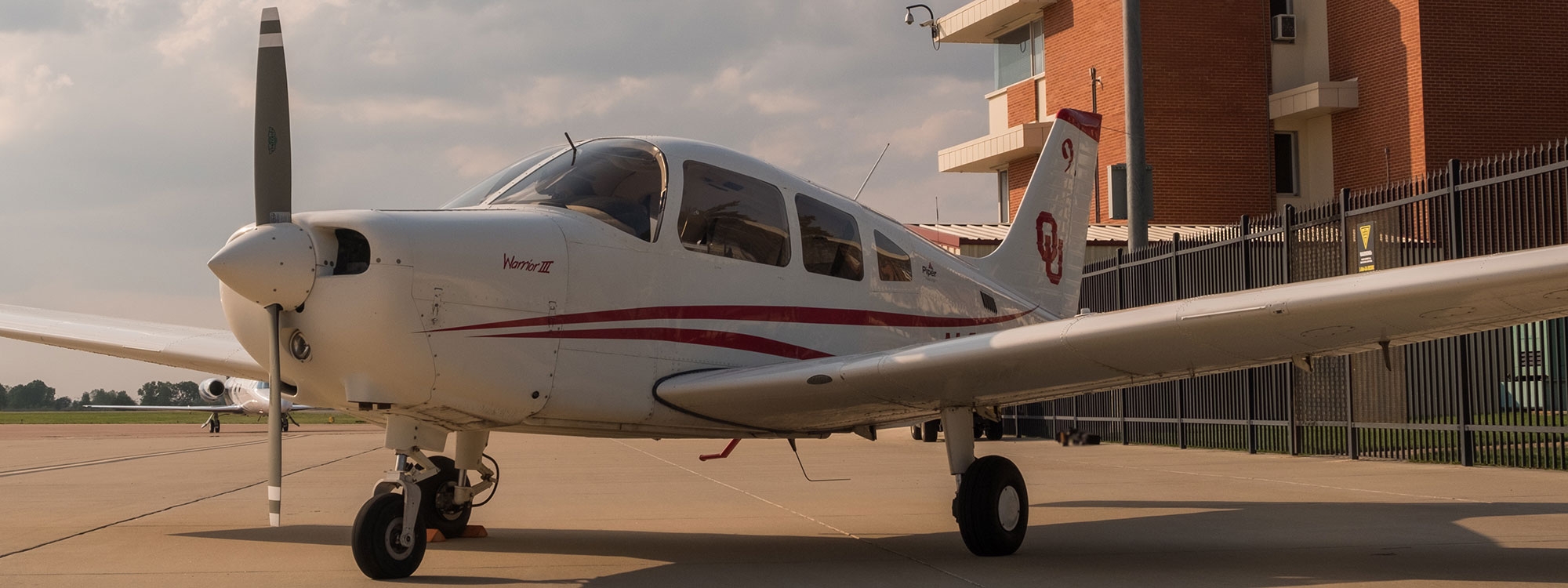 A P A 44-180 Seminole aircraft in front of a control tower.