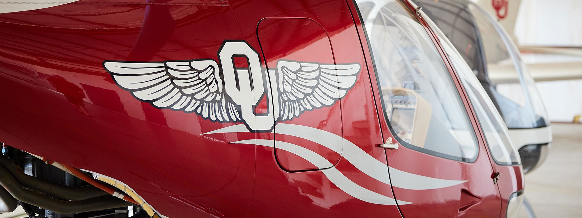 A Guimbal Cabri G2 helicopter with an O U insignia with wings on the side.