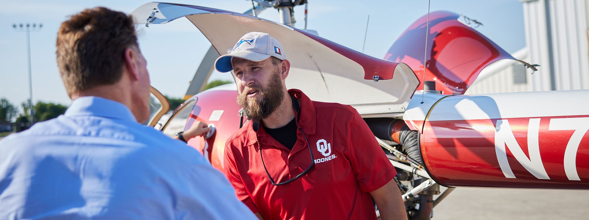 A person wearing an O U Sooners shirt shakes hands with another person.