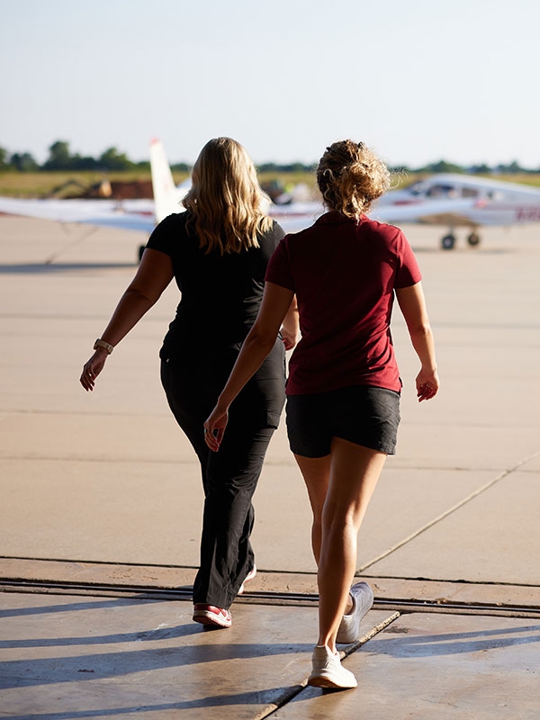 Two O U aviation students walking towards airplanes.