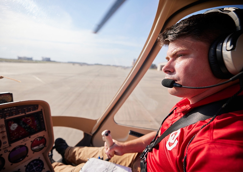 An OU helicopter pilot at the controls of a helicopter.