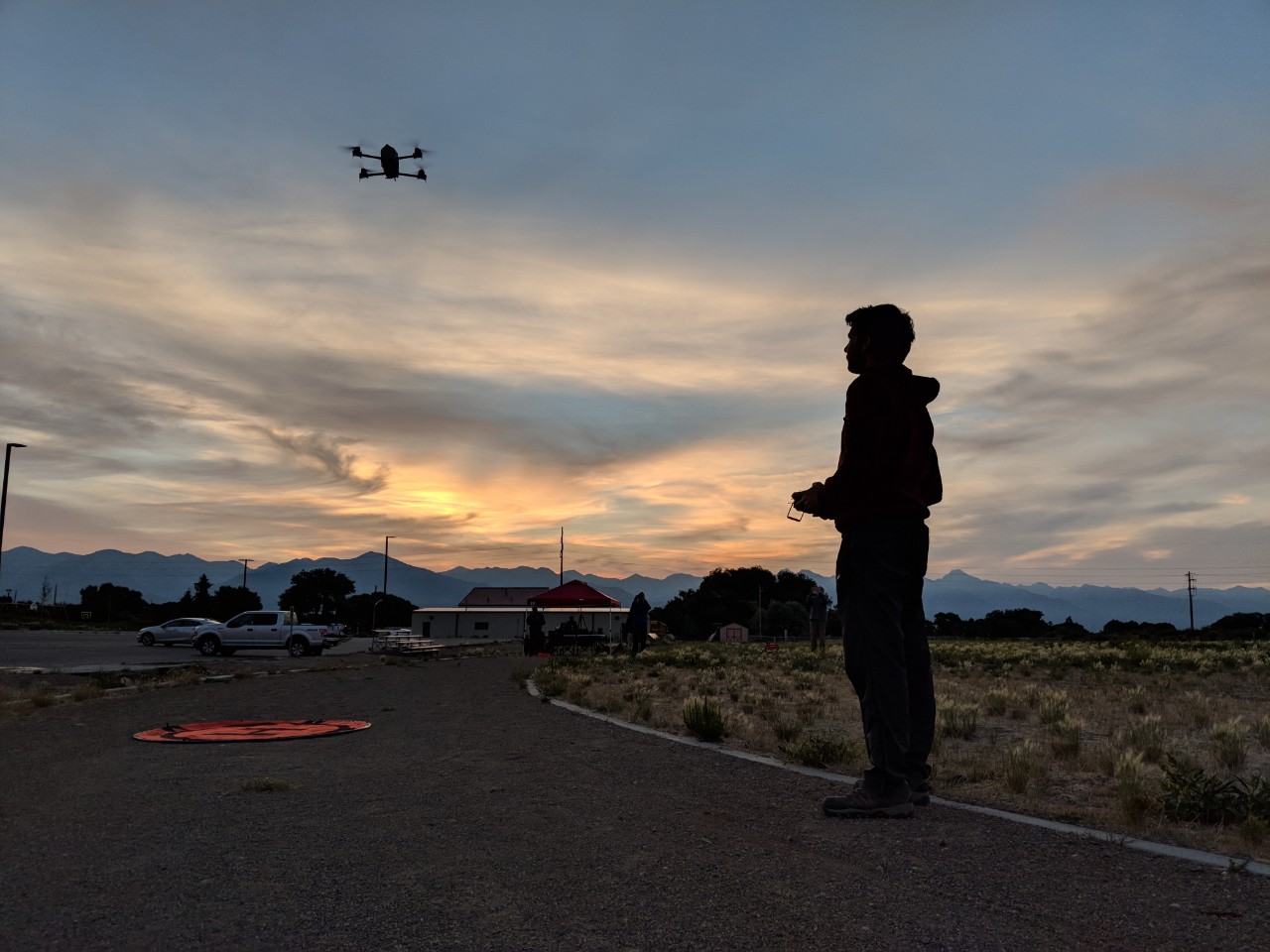 A meteorology major operates a drone, against the beautiful backdrop of a fading Oklahoma sunset.