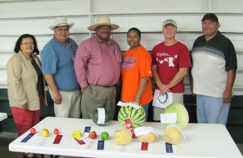 Randy Peppler with friends behind a table with various prized fruits and vegetables