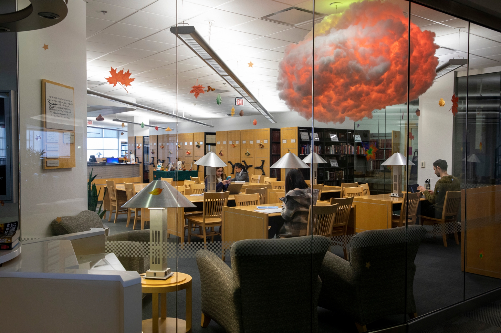 NWC Library with fall decorations, the orange leaves compliment the orange colored cloud behind the glass wall.