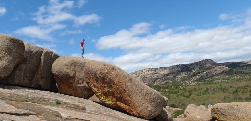 A student stands on top of a very large boulder during a field trip to the Wichita Mountains.