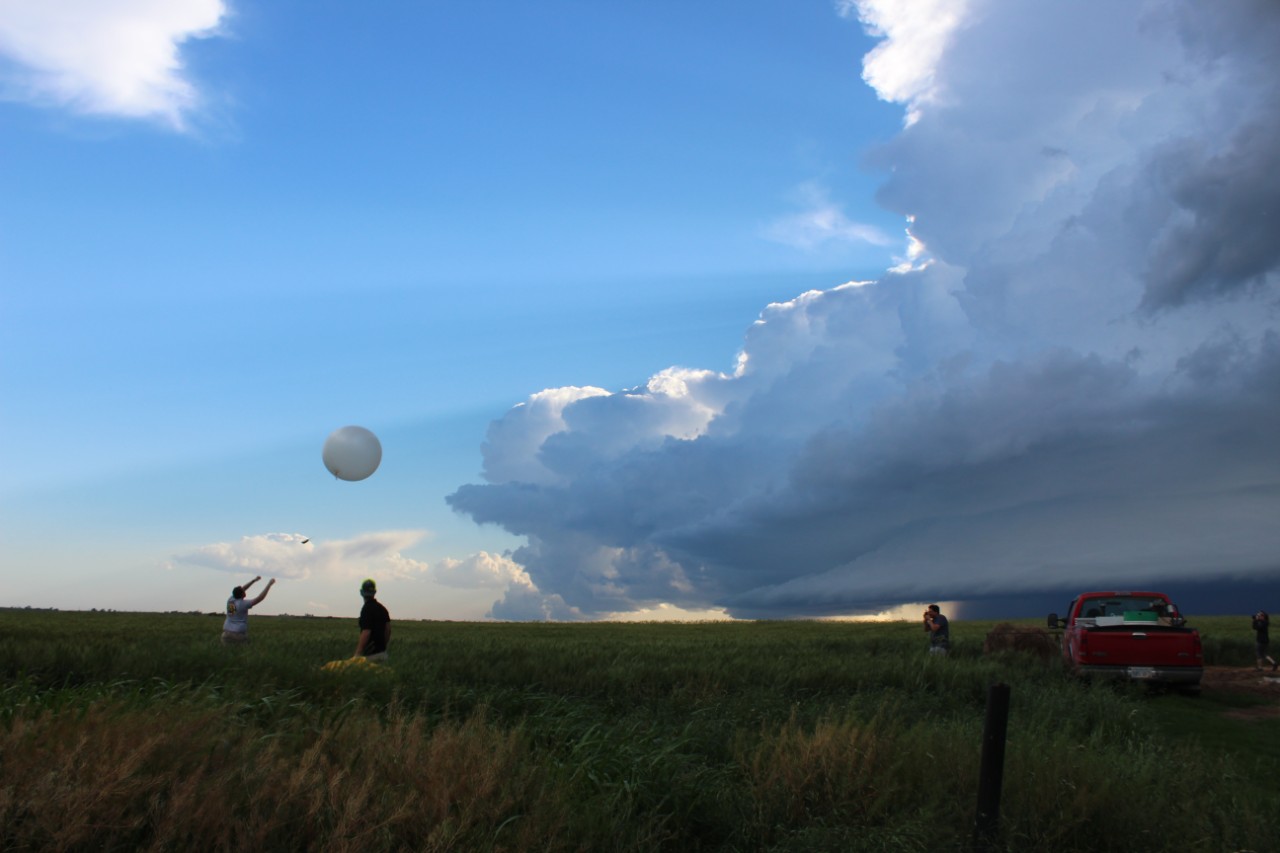 With a storm looming on the horizon, two students prepare a large, brightly colored weather balloon for launch. Photo courtesy of NOAA.