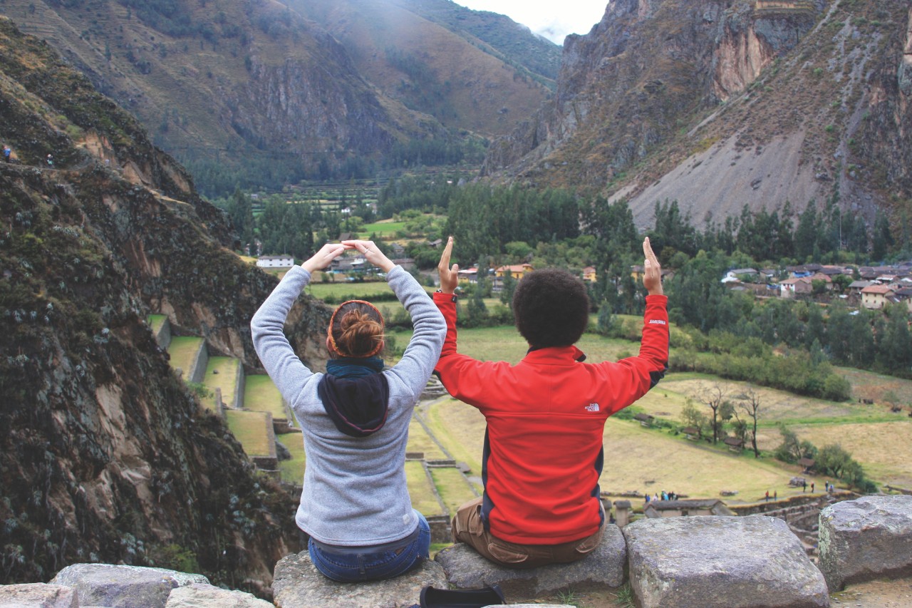 Two students overlooking a valley forming the "OU" with their arms