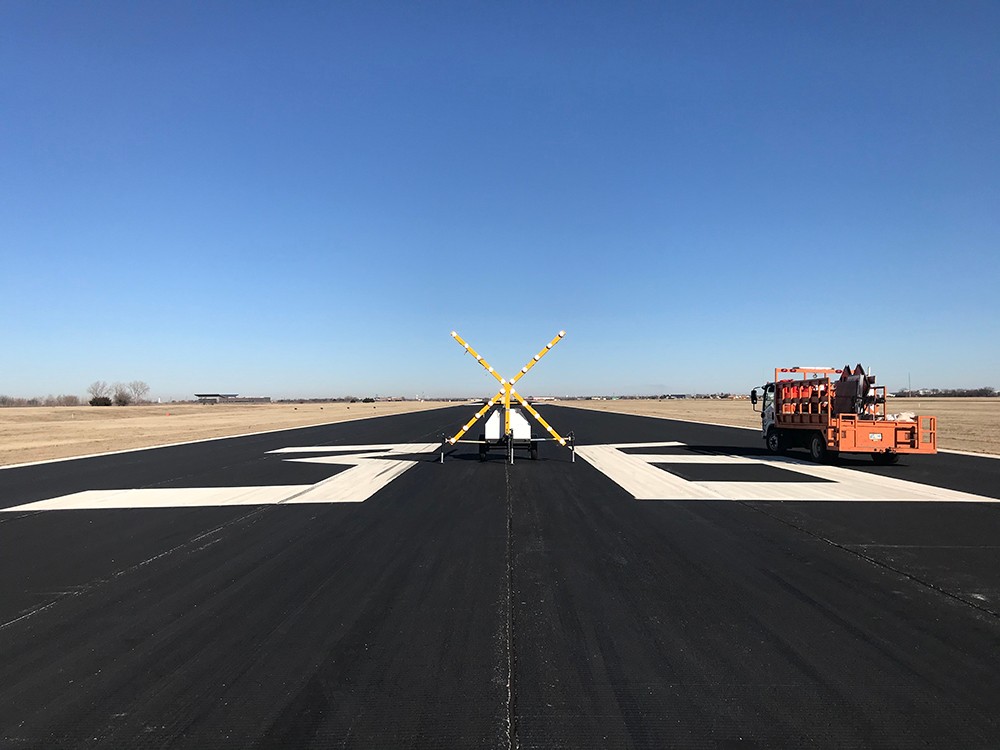 An airport runway (Runway 36) with a blue sky.