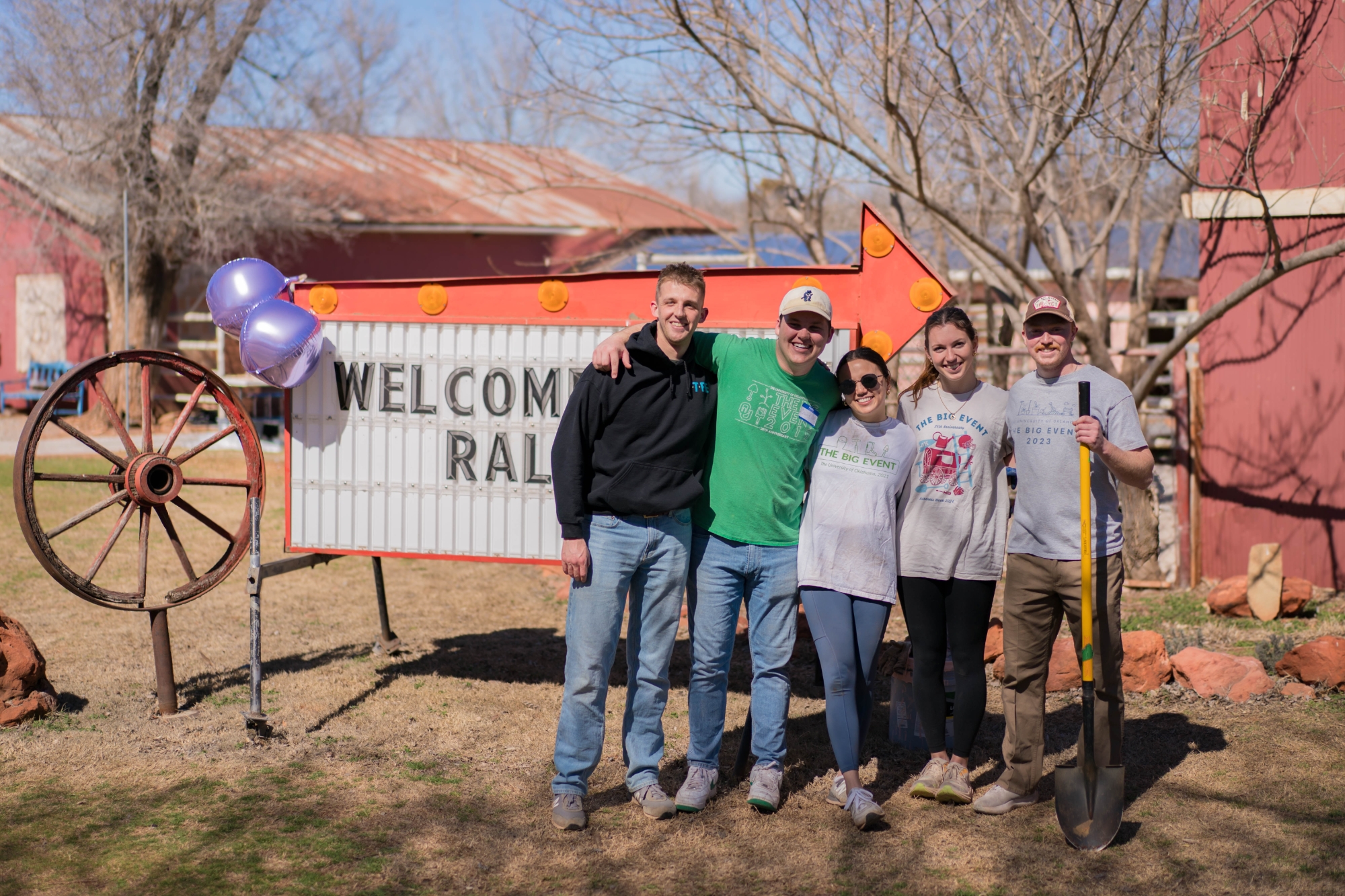 Big Event Alumni standing in front of a sign at a farm.