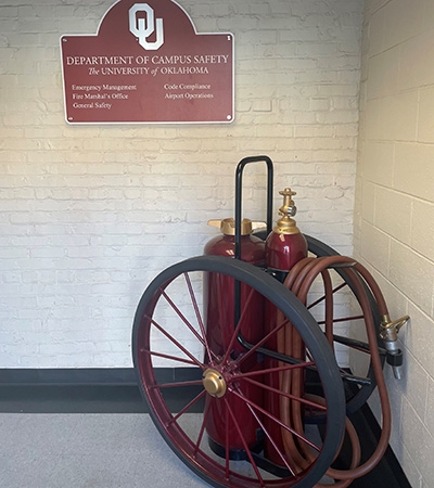 An antique firehose with a Department of Campus Safety plaque.