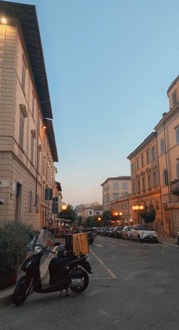 Buildings and cars lining the streets of Arezzo, Italy at dusk