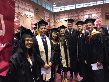 Photo of seven students in caps and gowns