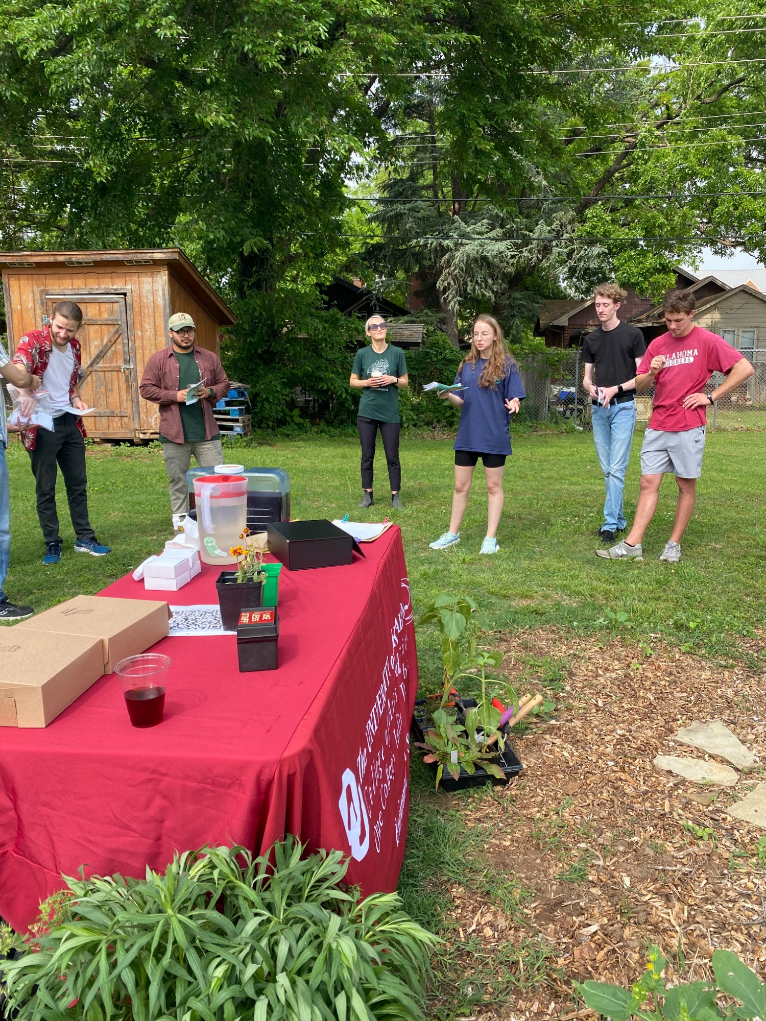 Students stand behind a table presenting at a garden event.