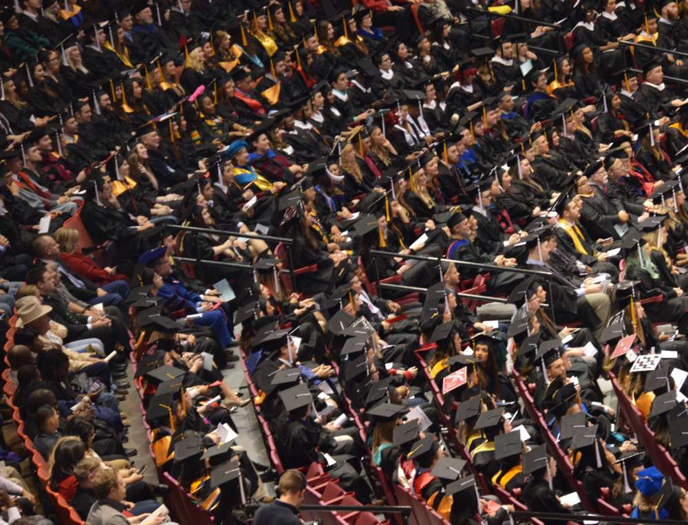 Students in graduation regalia attending Commencement.