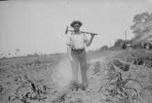 A man standing in a field during the dust bowl in black and white.