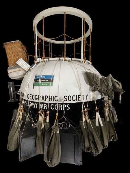 Ball shape cabin painted black & white "National Geographic Society & U.S. Army Air Corps" on side.. Exterior accessories include canvas ballast bags, intrument parachute bags, main parachute, battery boxes, and wicker spectrograph basket.