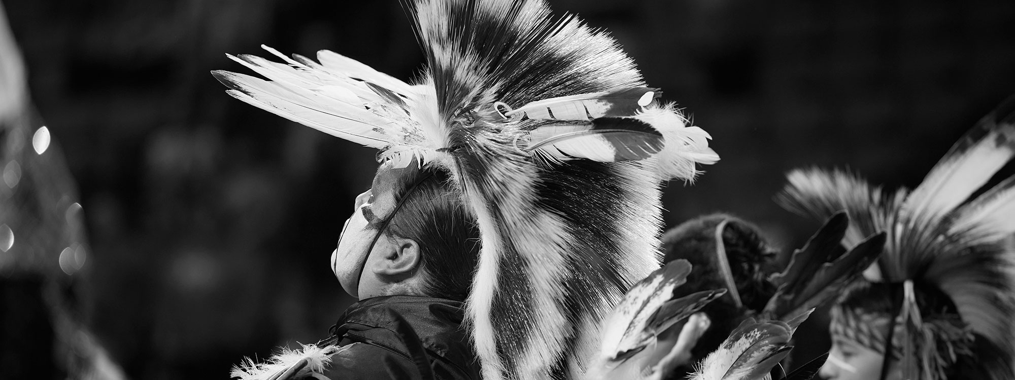 People wearing Native clothing, including headdresses, in black and white.
