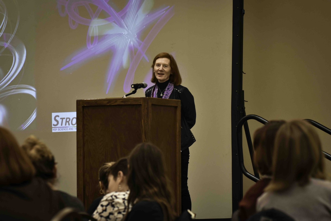 Someone addressing the CUWiP attendees from a podium on stage.