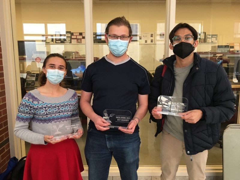 A photo of Cora, Alex, and Cosme holding up their Best Beginner awards at Hacklahoma.