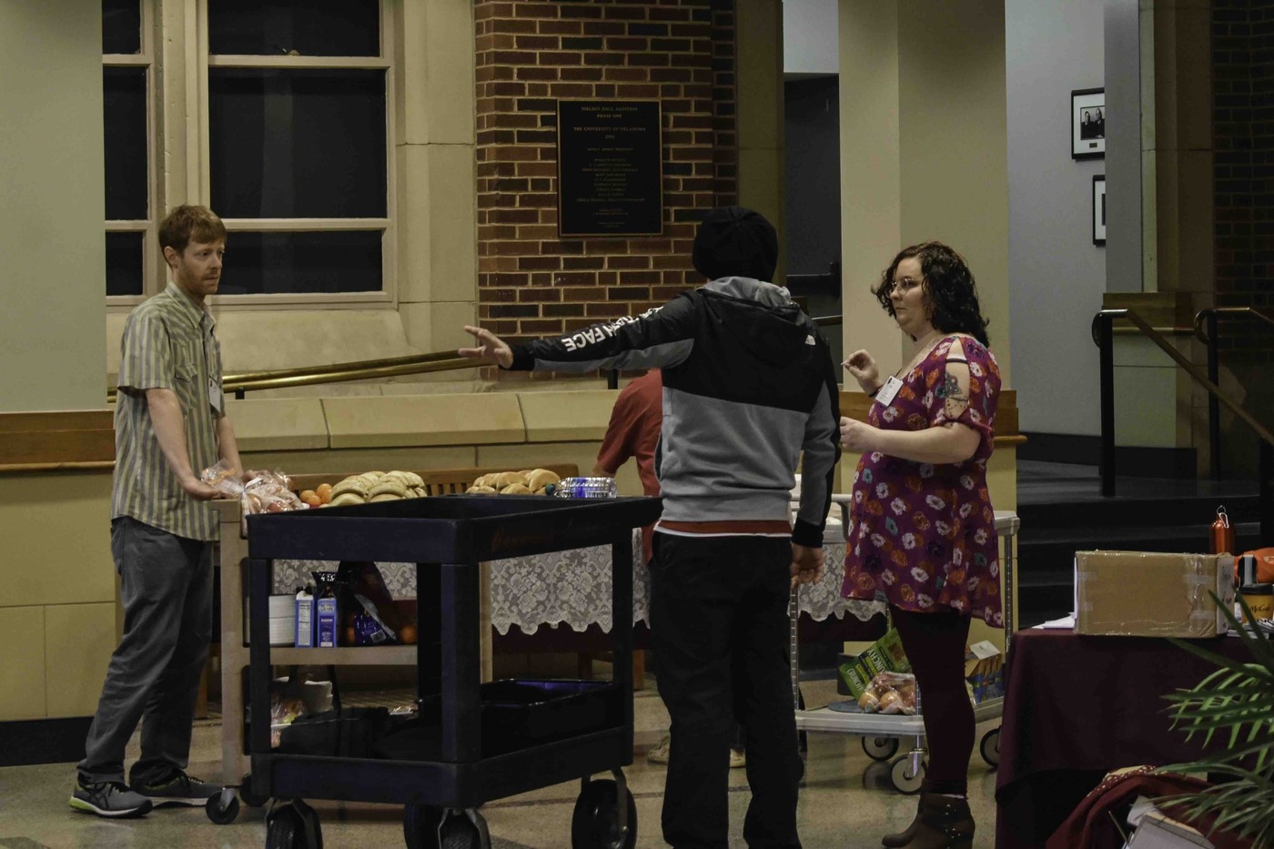People discuss where to place a cart of items at the conference.