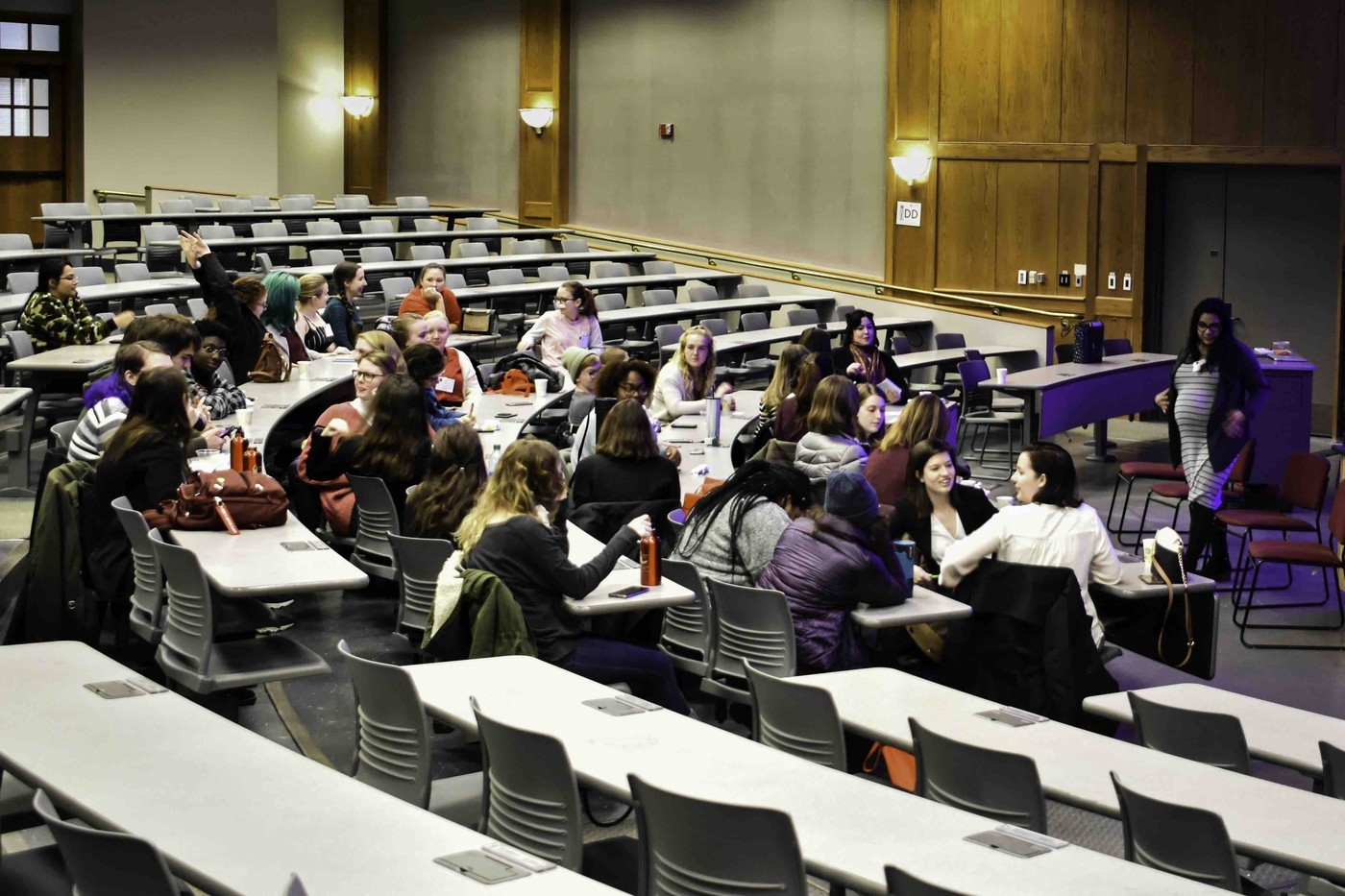 A group of attendees sit in a large lecture hall for a discussion.