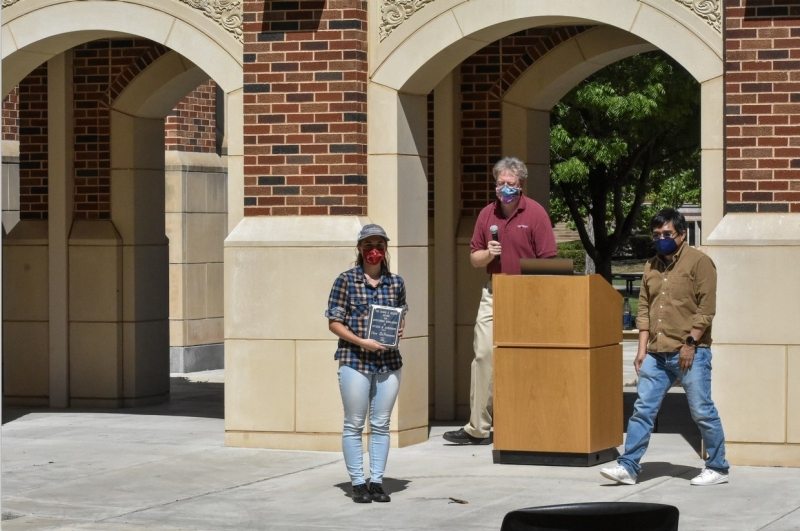 A student holds up their award.