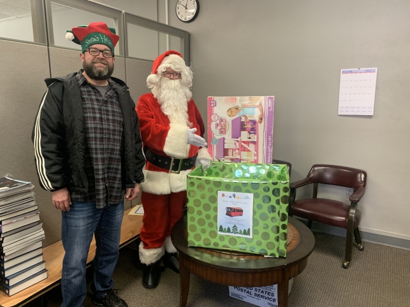 Someone dressed as Santa and his helper with an elf hat pick up donations for the toy drive.